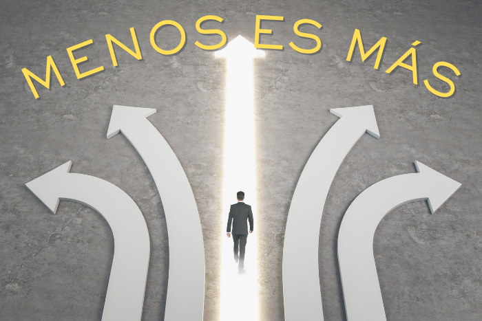 Cinco flechas que representan posibles caminos, con la flecha central iluminada y un hombre caminando por ella, que terminan con la frase "menos es más", que representa la conclusión del artículo La Paradoja de la Elección + 3 estrategias para vencerla: ¡Supera la Parálisis y Potencia tu Productividad!