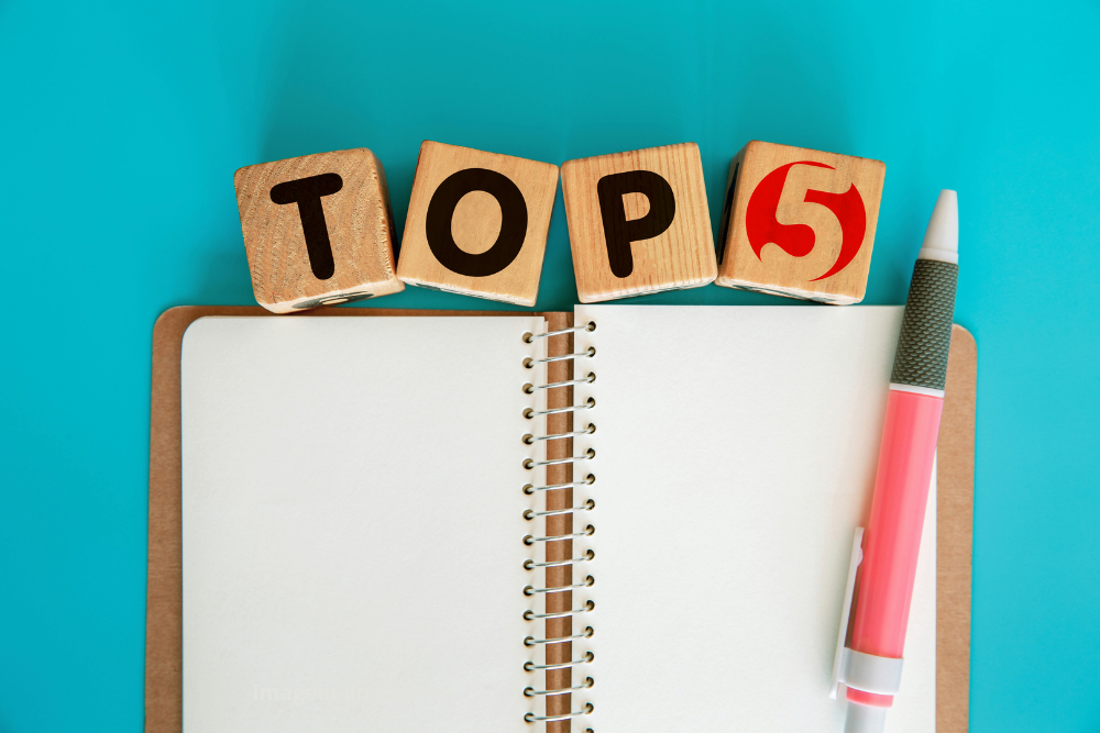 Montaje fotográfico con cuaderno y bolígrafo, simbolizando notas y haciendo referencia a la placa TOP5.